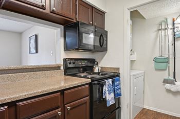 A kitchen with a black stove top oven and a black microwave above it